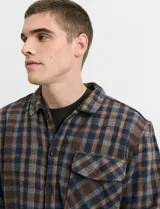 Sobrecamisa de manga larga con diseño a cuadros, cuello camisero y bolsillos laterales. Presenta un interior forrado con textura símil corderito y cierre frontal con botones.