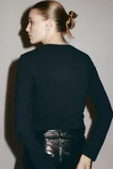 Remera negra de manga larga, entallada, con escote cuadrado pronunciado.