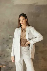 Blazer sastrero de corte recto y fit relajado, confeccionado en lino con hilos de lurex. Presenta solapas clásicas, hombreras, cierre frontal con un botón de nácar y bolsillos laterales con solapa.