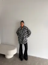 Buzo de peluche con estampado animal print, cuello alto con cierre frontal parcial y detalle de etiqueta decorativa en el pecho.