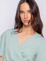 Blusa verde agua con textura acanalada, escote en V, mangas cortas amplias y lazo para atar en la cintura.