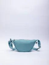 Riñonera semicircular color celeste de nylon con correa regulable, cierre superior y elásticos en los laterales.
