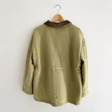 Chaqueta de silueta relajada, confeccionada en paño de lana color verde militar con detalles en pana de algodón marrón en el cuello y los bolsillos. Cuenta con cuello alto, bolsillos frontales amplios y cordón regulable en la cintura.