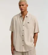 Camisa de corte relajado para hombre, confeccionada en una mezcla de cáñamo y algodón. Presenta cuello inglés, manga corta, cierre frontal con botones y un bolsillo en el pecho con una pequeña etiqueta aplicada.