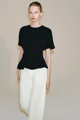 Camiseta de algodón con cuello redondo y manga corta. Presenta un diseño entallado con pinzas en la cintura y bajo recto.