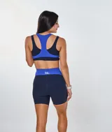 Conjunto deportivo compuesto por un top de escote redondo con espalda estilo nadador y un short de tiro alto. Ambas piezas presentan un diseño bicolor en azul eléctrico y azul marino, confeccionadas en tejido acanalado con el logo de la marca estampado en el frente del top.
