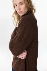 Campera de punto tejido color beige con diseño de ochos, cuello alto y cierre frontal completo.