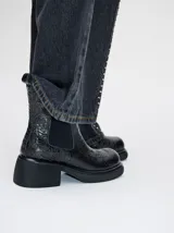 Bota tipo chelsea de cuero vacuno en color rojo con estampado floral grabado en negro. Presenta paneles laterales elásticos, suela de plataforma y taco cuadrado en color negro.