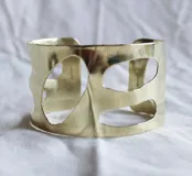 Brazalete rígido de bronce color dorado con diseño calado irregular.