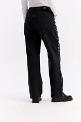 Jean wide leg de tiro medio en color negro, con diseño de corte amplio y detalle de tachas metálicas a lo largo de los laterales y en los bolsillos delanteros.