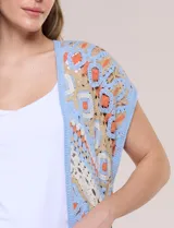 Cardigan tejido al crochet de color celeste, beige y naranja, con diseño geométrico y flecos en el ruedo.