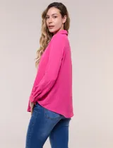 Blusa verde de calce holgado y caída fluida, confeccionada en tejido tipo crepé. Cuenta con cuello camisero con solapa, escote en V y cierre parcial al frente con tres botones metálicos. Las mangas son largas con puños abotonados.