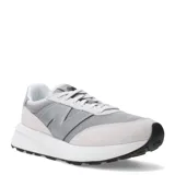 Championes New Balance modelo U370, de estilo retro y perfil bajo. Presentan un diseño en tonos grises, combinando paneles de malla textil con refuerzos de gamuza. Incluyen el logo característico en los laterales, cierre mediante cordones y una suela de goma con entresuela blanca.