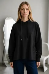 Buzo tipo canguro de corte oversize, color marrón oscuro, con capucha y cordones ajustables. Presenta costuras verticales decorativas, bolsillos laterales y ruedo con terminación desflecada.