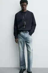 Camiseta de manga larga con cuello redondo, confeccionada en algodón compacto y pesado, con diseño de corte relajado y costuras decorativas en el cuello.