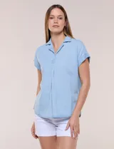Blusa de diseño recto y textura suave de denim liviano color celeste, con cuello solapa abierto en V, pechera con detalle pespunteado y pliegue central. Presenta mangas cortas caídas con dobladillo fijo y ruedo ligeramente curvo.