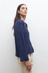 Sweater de punto calado en color azul, con cuello polo y escote en V. Presenta mangas largas con puños rectos y un diseño de tejido vertical.