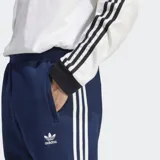 Pantalón de jogging azul marino con tres rayas blancas a los costados y logo de Adidas bordado en el muslo.