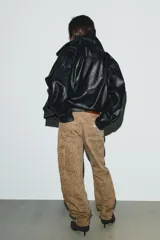 Jeans tiro medio, corte baggy balloon, color marrón claro con estampado animal moteado en tono más oscuro. Presenta bolsillos laterales, bolsillos cargo con solapa en las piernas y bolsillos de plastrón en la espalda. El bajo es ajustable con botón a presión.