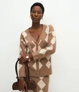 Cardigan de punto con estampado de cuadros argyle en tonos marrón y beige. Presenta escote en V, cierre frontal con botones, mangas largas con puños acanalados y corte recto.