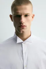 Camisa slim fit de algodón en color blanco, con cuello smoking y manga larga con puño doble abotonado.