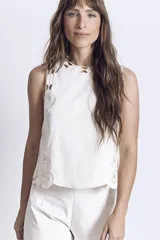 Blusa negra sin mangas, de corte recto y escote redondo, con detalles de bordados contrastantes en color blanco en los bordes y costados.
