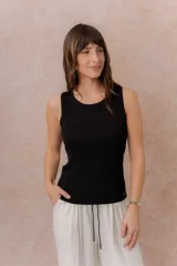 Musculosa de tejido fino con textura acanalada, color blanco, escote redondo y hombros anchos.