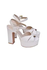 Sandalias de plataforma con tacón de bloque alto, confeccionadas en cuero vacuno color crema. Presentan diseño de tiras cruzadas en el empeine y pulsera ajustable al tobillo con hebilla metálica.