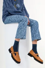 Mocasines color marrón claro con detalle de hebilla y diseño artesanal en la parte frontal con pasamanería. Suela track color negro.