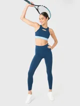 Top deportivo de entrenamiento con diseño de cuello alto y detalle de apertura frontal sobre el busto. Presenta una banda elástica inferior en tono celeste contrastante y almohadillas removibles.