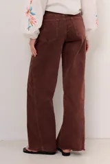 Jean de corte wide leg y tiro medio, con diseño de perneras amplias y terminación desmechada en el bajo.