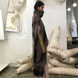 Poncho de lana merino afieltrada color marrón con cuello alto y abertura frontal.