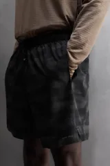 Short deportivo negro con estampado abstracto, cintura elástica ajustable con cordón, bolsillos laterales y trasero con cierre, forro interior y detalle de perforaciones en el ruedo.