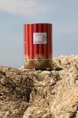 Pareo rectangular fucsia con estampado de sol dorado y borde con diseño geométrico en tonos naranja y marrón.