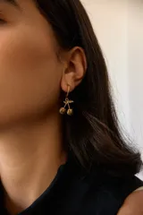 Aros de acero quirúrgico hipoalergénico, con argolla pequeña y dije colgante en forma de cerezas.