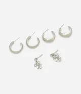 Kit de tres pares de caravanas plateadas. Incluye dos pares de aros tipo argolla de diferentes tamaños y un par de caravanas con forma de lazo y detalles de circonia.