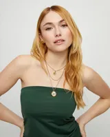 Collar triple dorado con cadena fina y dos dijes de ojo con cristal verde facetado. El collar es de aleación de metales bañado en oro de 18k.