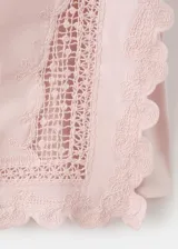 Top de algodón color rosado, con detalles bordados, cuello redondo, mangas cortas y terminaciones festoneadas.