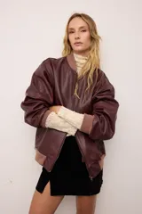 Campera bomber de cuero vacuno en color bordó, con diseño oversized y corte bombé. Presenta cierre frontal, bolsillos laterales y terminaciones de puños, cuello y pretina en tejido de algodón acanalado a tono.