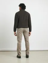 Pantalón de vestir verde oliva, de corte slim fit, sin pinzas, con bolsillos laterales y traseros. Se ajusta a la cintura con cinturón de cuero marrón.