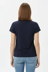 Remera de algodón color beige, de manga corta con vuelta, cuello redondo y estampa frontal de flores con lazo en tonos azules y celestes.