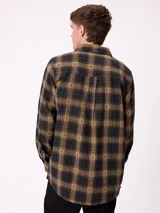 Camisa de manga larga confeccionada en franela de algodón, con diseño de cuadros en tonos verde y marrón. Presenta cuello clásico, cierre frontal con botones y dos bolsillos en el pecho con solapa.