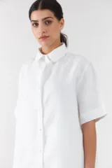 Camisa blanca de manga corta y corte recto, con cuello camisero clásico y cierre frontal de botones.