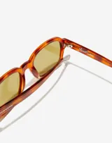 Lentes de sol unisex con armazón de acetato en tono carey y cristales amarillos. Presentan un diseño de marco cuadrado con detalles metálicos en las esquinas y la firma de Manuel Turizo en el interior de la patilla.