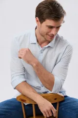 Camisa de lino rayada de manga larga, con cuello camisero, cierre frontal de botones y bordado sutil en el pecho.