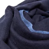 Bufanda de tejido de punto bicolor, con un lado en azul claro y el otro en azul oscuro, terminada con flecos en los extremos.