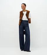 Pantalón de jean corte wide leg en color azul oscuro, con cintura alta, cierre frontal con botón y cremallera, y cinturón de lazo del mismo tejido.