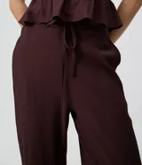 Pantalón palazzo de viscosa texturizada color marrón, de tiro alto con cintura elástica, lazo frontal regulable y bolsillos laterales.