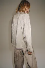 Blazer de estilo oriental confeccionado en hilatura de viscosa con tejido jacquard tono sobre tono. Presenta escote en pico, manga larga y cierre frontal cruzado con alamares a tono.