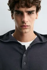 Jersey de punto de corte regular, confeccionado en una mezcla de algodón y lana. Presenta capucha, manga larga y cierre frontal con botonadura.